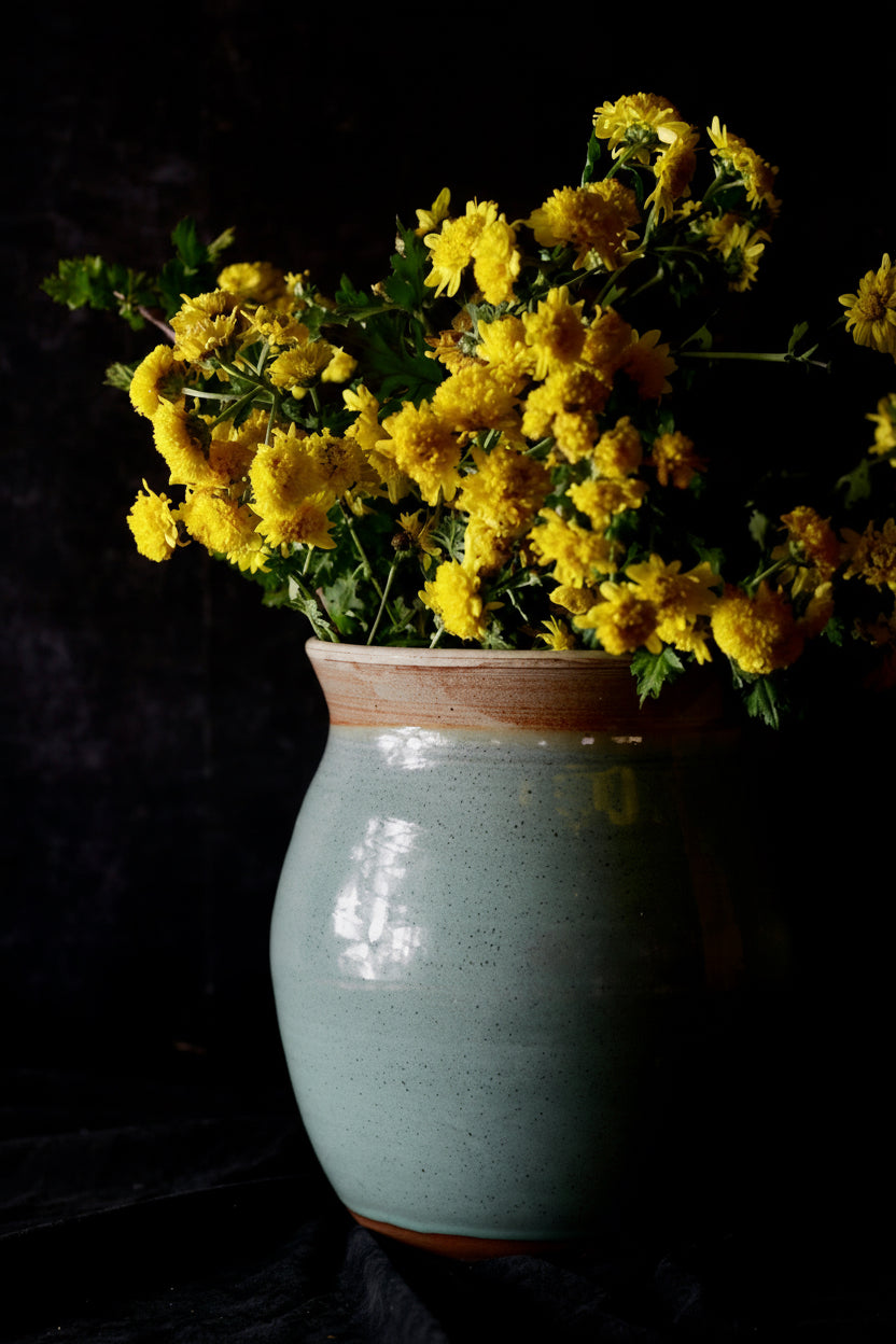 Ceramic vase with yellow flowers on a dark background