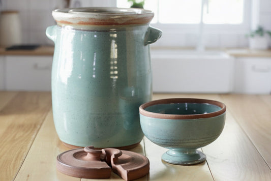 Set of ceramic containers on a wooden surface with a cabbage in the background