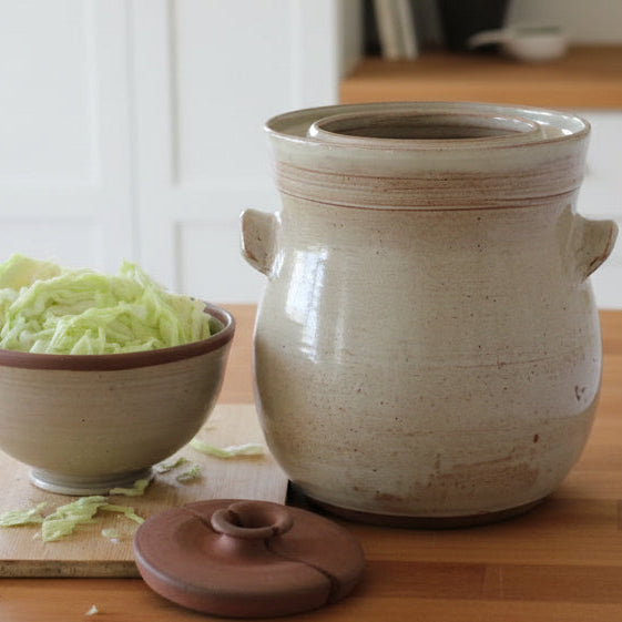 Ceramic crock with cabbage on a wooden surface